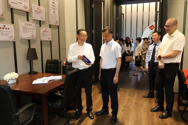 广西税务局党委委员、总经济师黄尚书（左二）和柳州职业技术大学党委书记刘子林（左一）在柳州市高校税收普法教育实践站税收普法教育研究室翻阅税法知识读本